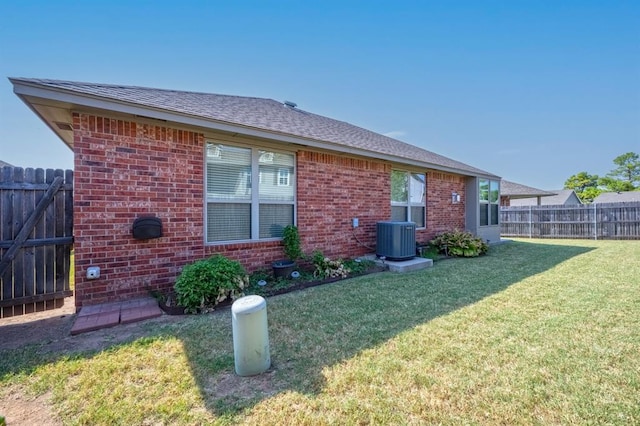 rear view of property with central AC and a lawn