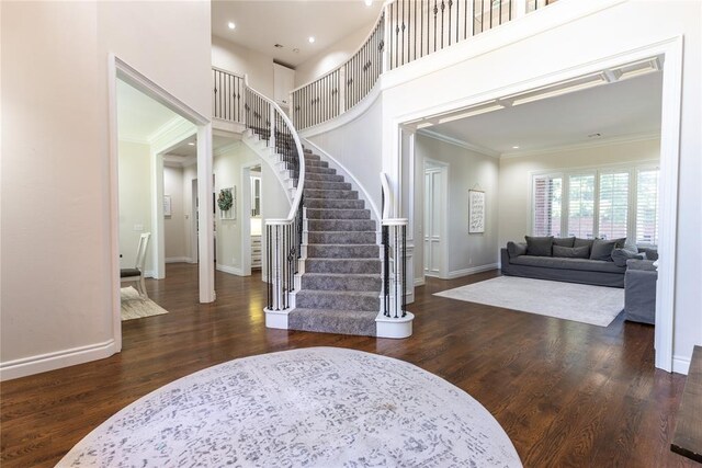 entrance foyer with crown molding, dark hardwood / wood-style flooring, and a towering ceiling