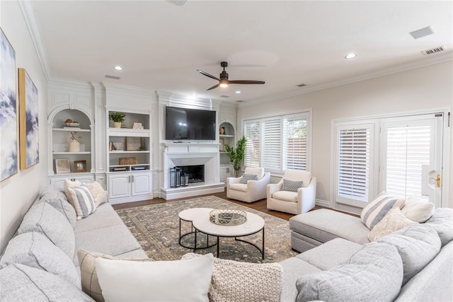 living room with hardwood / wood-style flooring, ceiling fan, and crown molding