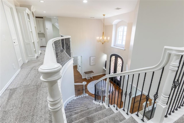 staircase with a chandelier and carpet