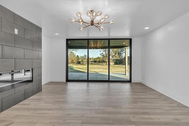 unfurnished dining area with light wood-type flooring and an inviting chandelier