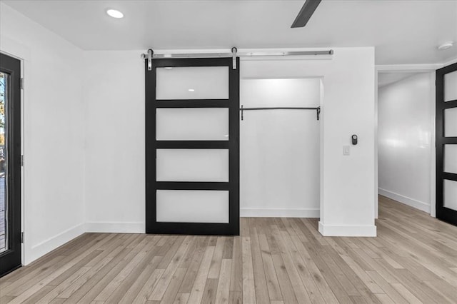 interior space featuring ceiling fan, a barn door, and light hardwood / wood-style floors