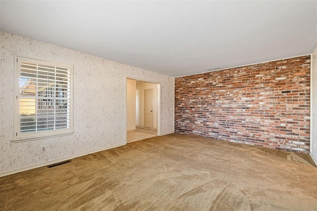 carpeted spare room featuring brick wall