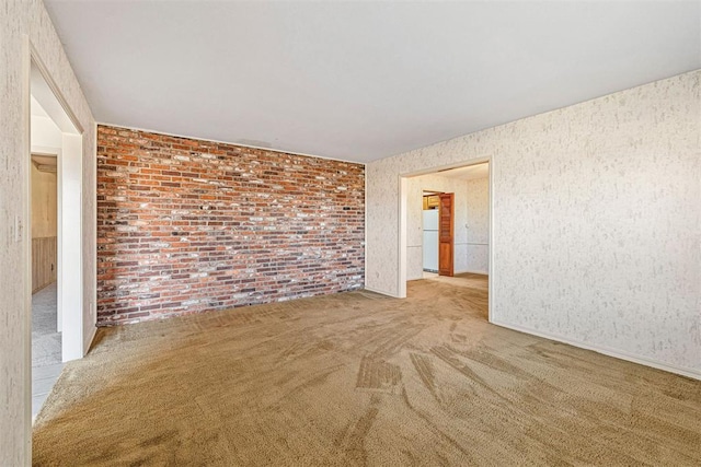 carpeted spare room with brick wall