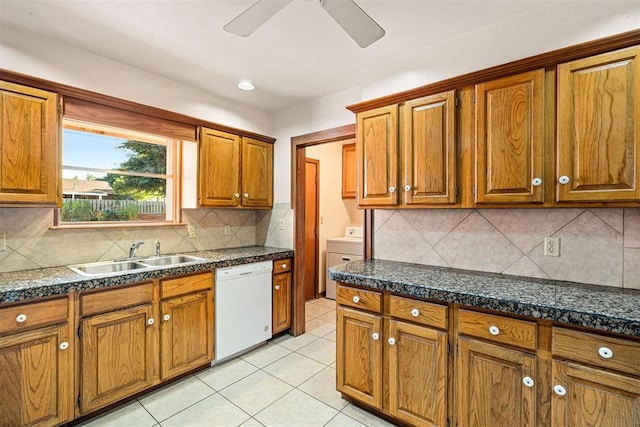 kitchen featuring sink, tasteful backsplash, washer / clothes dryer, white dishwasher, and light tile patterned flooring