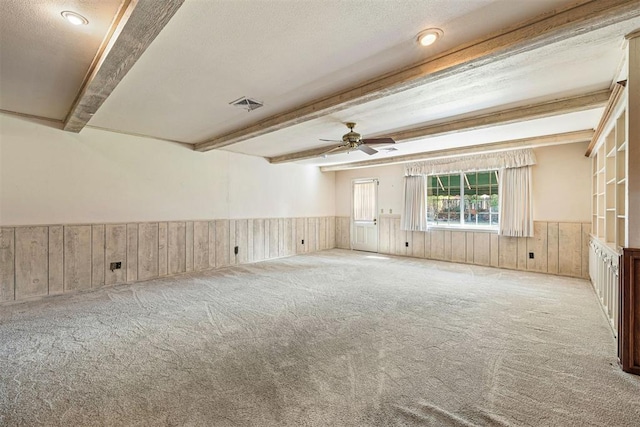 empty room featuring beam ceiling, light carpet, ceiling fan, and a textured ceiling