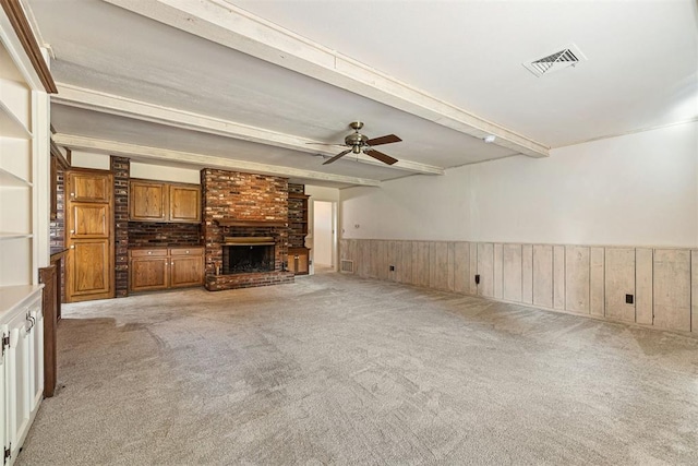 unfurnished living room with ceiling fan, wood walls, light carpet, and a brick fireplace