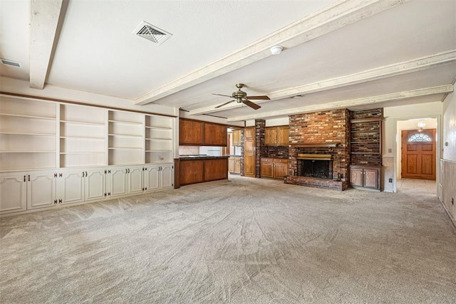 unfurnished living room with a fireplace, beam ceiling, light colored carpet, and ceiling fan