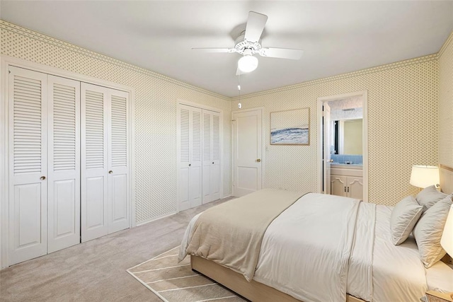 carpeted bedroom featuring ceiling fan, connected bathroom, and two closets