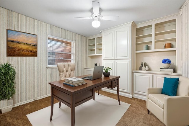 carpeted office with built in shelves and ceiling fan