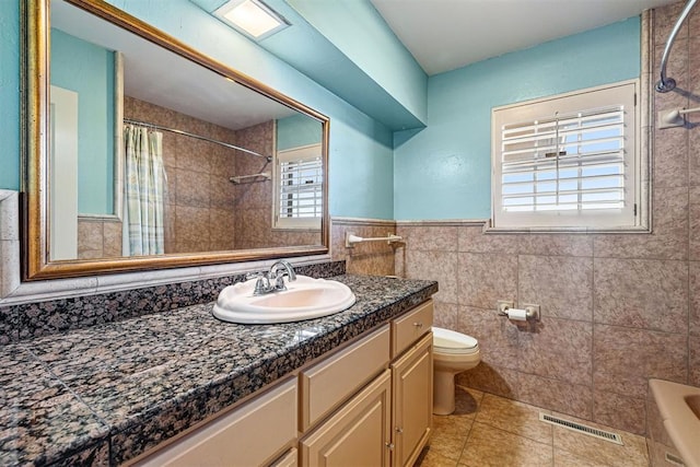 full bathroom featuring shower / bath combination with curtain, tile patterned floors, vanity, tile walls, and toilet