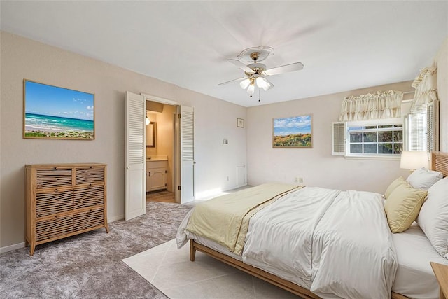 carpeted bedroom with ensuite bathroom and ceiling fan