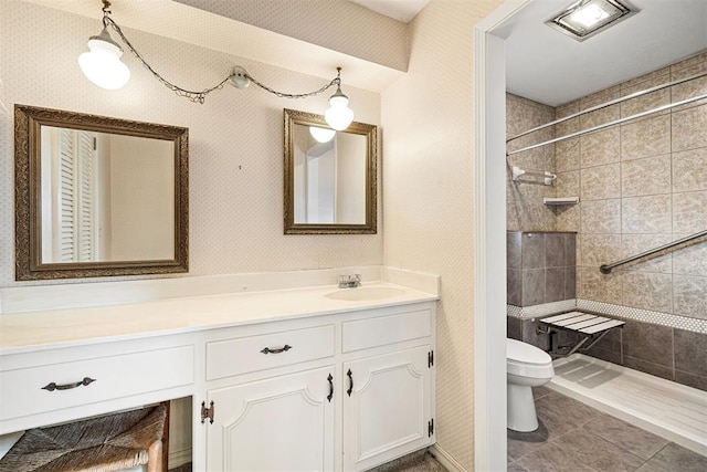 bathroom with toilet, a tile shower, vanity, and tile patterned floors