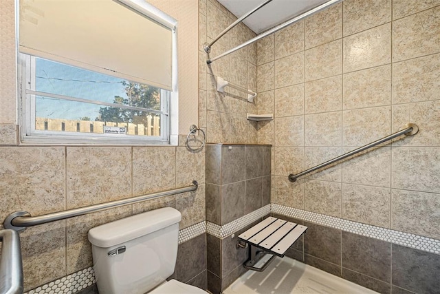 bathroom featuring tiled shower, toilet, and tile walls