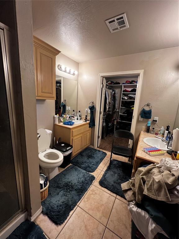 bathroom with toilet, vanity, tile patterned floors, and walk in shower