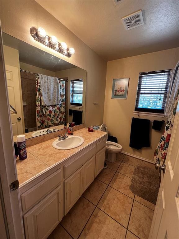 bathroom with tile patterned floors, vanity, toilet, and walk in shower