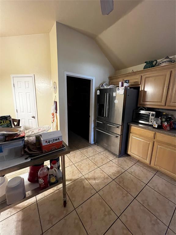 kitchen with high end refrigerator, light tile patterned floors, vaulted ceiling, and ceiling fan