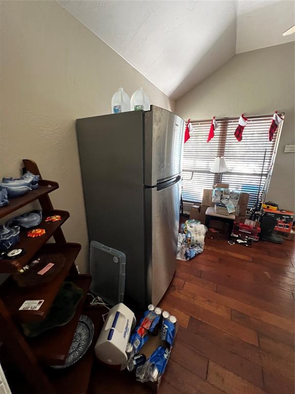 kitchen with stainless steel fridge, dark wood-type flooring, and lofted ceiling