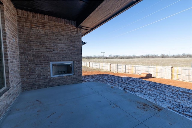 view of patio featuring an outdoor brick fireplace and a rural view