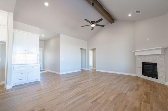 unfurnished living room with beamed ceiling, a fireplace, light hardwood / wood-style floors, high vaulted ceiling, and ceiling fan