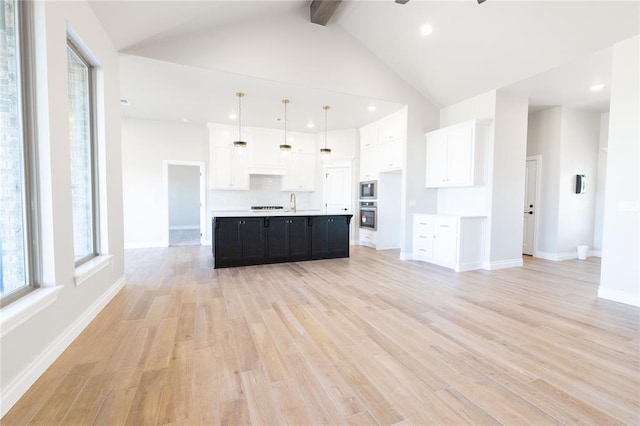 kitchen with light countertops, light wood-type flooring, dark cabinets, white cabinetry, and high vaulted ceiling