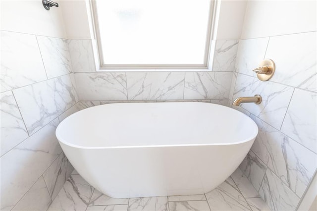 full bathroom with marble finish floor and a soaking tub
