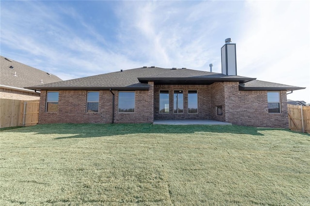 rear view of house featuring a yard, a fenced backyard, a patio, roof with shingles, and brick siding