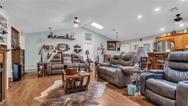 living room with light hardwood / wood-style flooring and vaulted ceiling with skylight