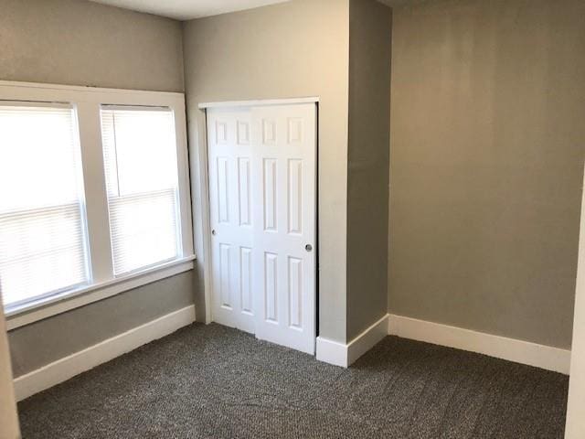 unfurnished bedroom with a closet and dark carpet