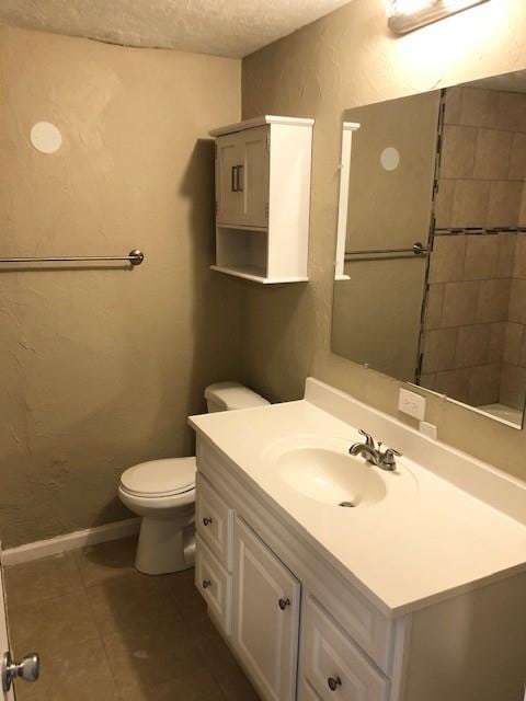 bathroom featuring tile patterned floors, vanity, a textured ceiling, and toilet