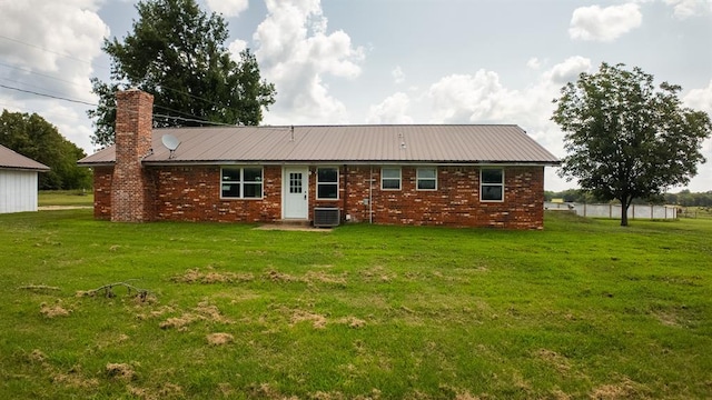 rear view of property featuring central AC unit and a lawn