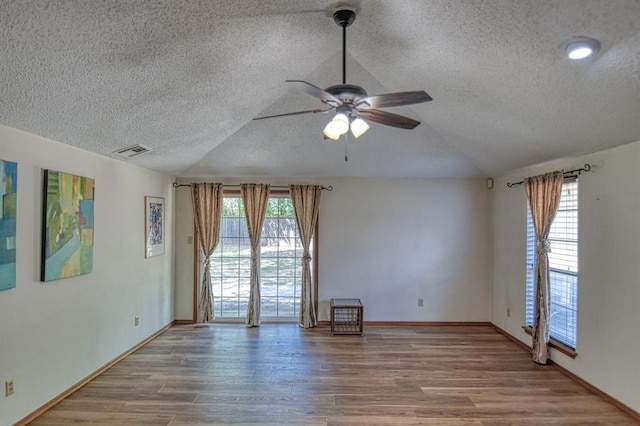 empty room featuring vaulted ceiling, ceiling fan, a textured ceiling, and hardwood / wood-style flooring