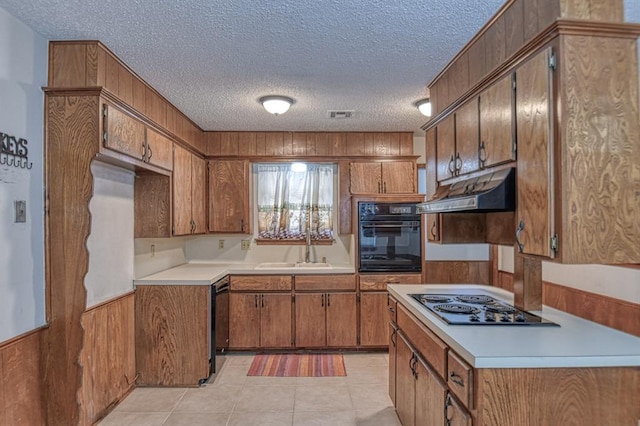 kitchen with sink, light tile patterned floors, black appliances, and a textured ceiling