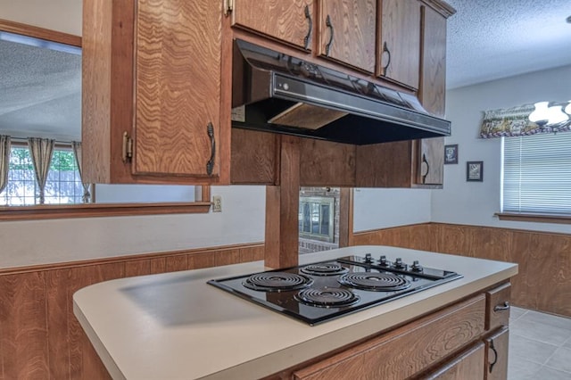 kitchen with light tile patterned flooring, a textured ceiling, an inviting chandelier, and electric cooktop