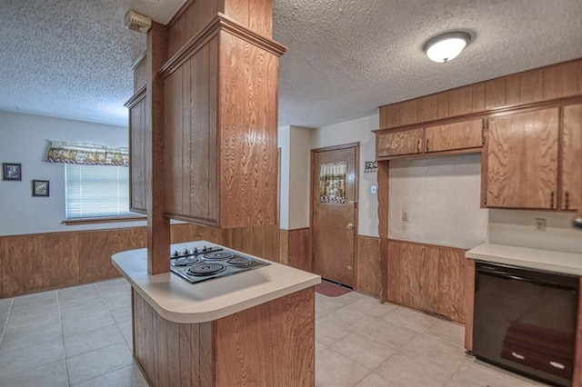 kitchen featuring kitchen peninsula, black dishwasher, wooden walls, and stainless steel cooktop