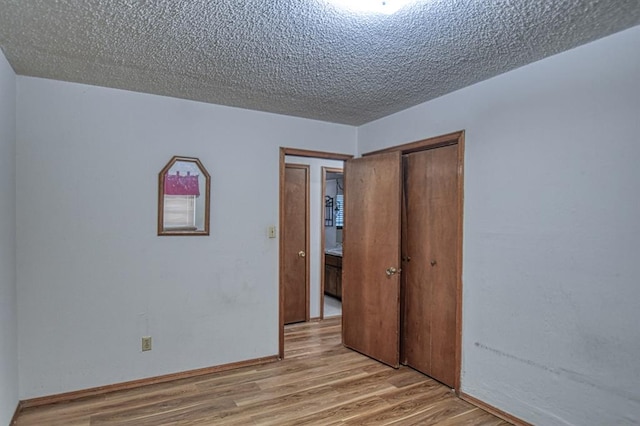 unfurnished bedroom featuring a closet, a textured ceiling, and light wood-type flooring