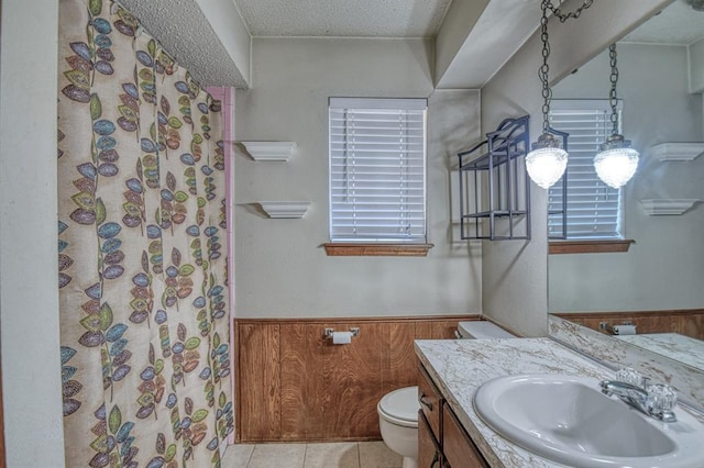 bathroom with wooden walls, vanity, a textured ceiling, and toilet