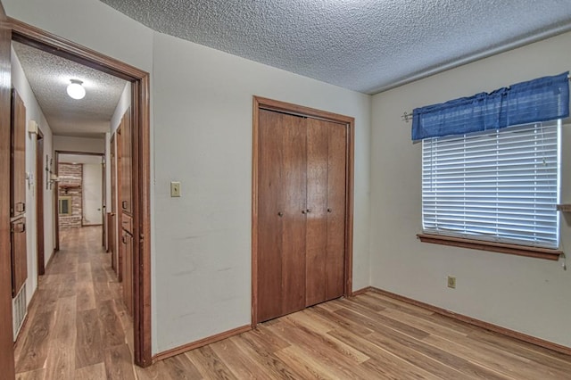 unfurnished bedroom featuring a textured ceiling, light hardwood / wood-style flooring, and a closet