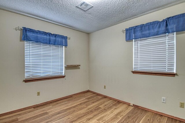 unfurnished room with a textured ceiling and hardwood / wood-style flooring