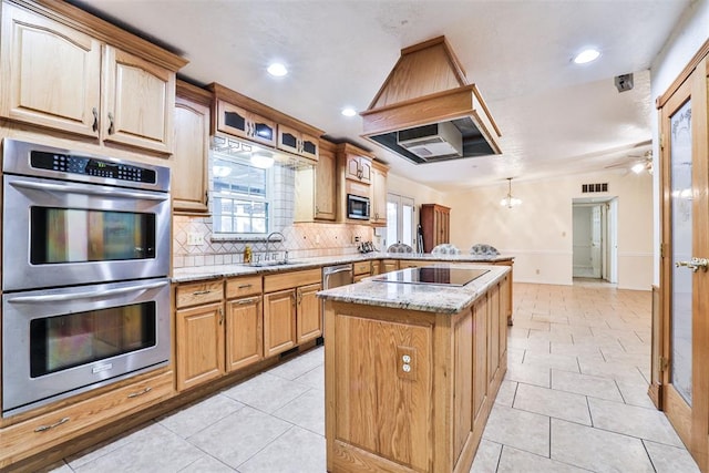 kitchen with tasteful backsplash, ceiling fan with notable chandelier, stainless steel appliances, sink, and a center island