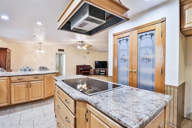 kitchen featuring light tile patterned flooring, black electric stovetop, ceiling fan with notable chandelier, light stone countertops, and a kitchen island