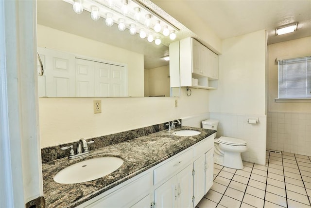 bathroom featuring tile patterned flooring, vanity, toilet, and tile walls