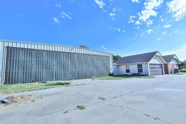 exterior space with cooling unit, a garage, and an outbuilding