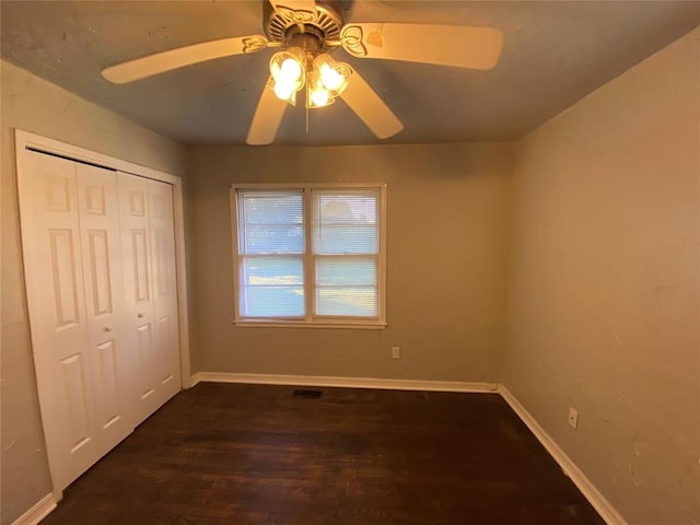 unfurnished bedroom with ceiling fan, a closet, and dark wood-type flooring