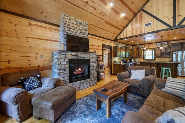 living room with a stone fireplace, high vaulted ceiling, wood-type flooring, wooden walls, and wood ceiling