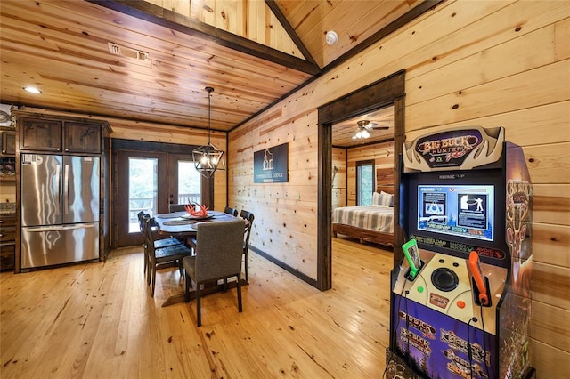 dining area featuring lofted ceiling, french doors, wooden walls, and light hardwood / wood-style flooring