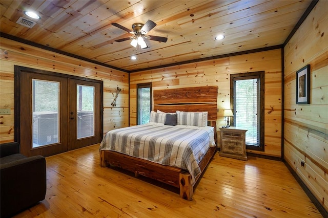 bedroom featuring light wood-type flooring, wooden walls, and multiple windows