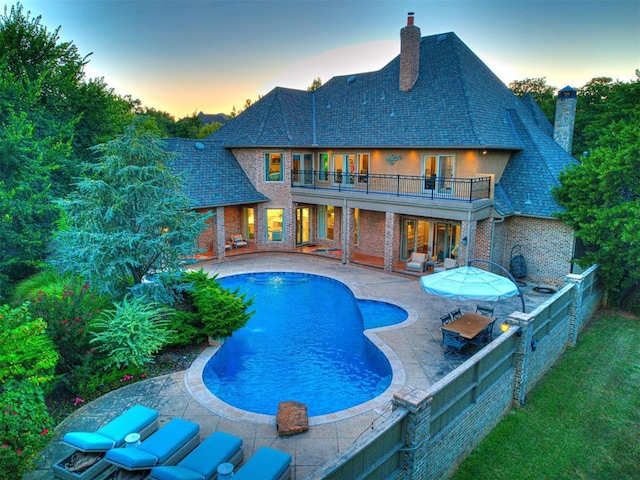 pool at dusk with a patio area