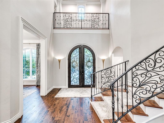 foyer featuring french doors, dark wood-type flooring, and a high ceiling