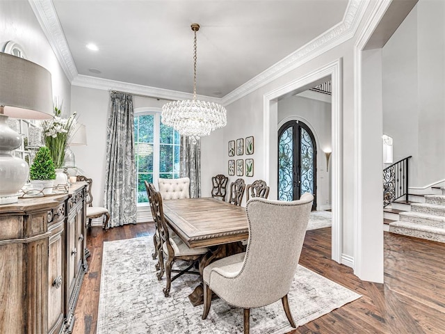 dining area featuring french doors, an inviting chandelier, dark wood-type flooring, and ornamental molding